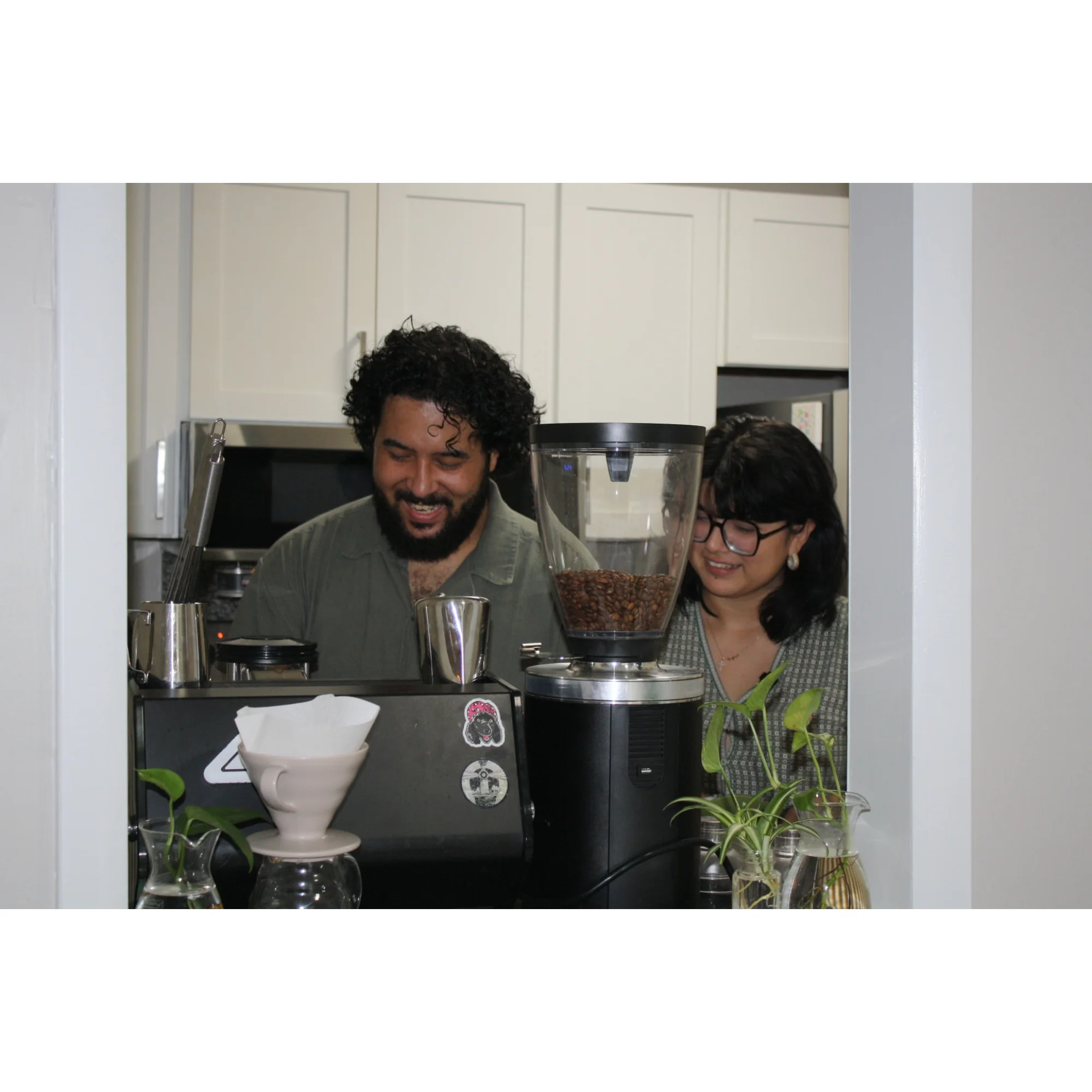 Natasha and Kero smiling together behind an espresso machine